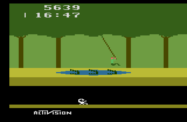 Pitfall! Atari 2600 Screenshot: Use the vines to swing over dangers.